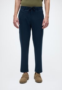 Pantalon bleu marine à rayures fines, fabriqué dans un tissu léger. Comprend une taille avec cordon de serrage et des jambes fuselées.