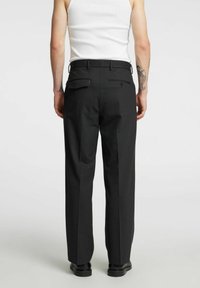Czarne, dopasowane spodnie o kroju prostych nóg, wyposażone w dwie tylne kieszenie, szlufki na pasek i gładką fakturę materiału.