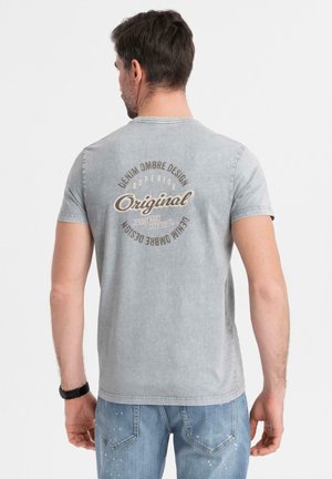Grå bomulds T-shirt med korte ærmer, ryggrafik i beige tekst med teksten "Denim Ombre Design Original" og falmet vasketekstur.