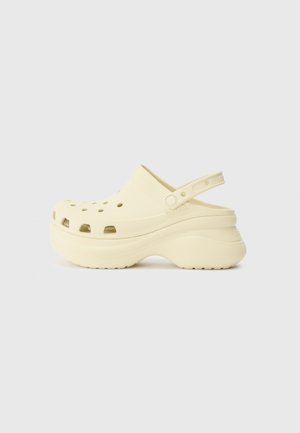 Yellow foam clog with perforations, a back strap, and a thick sole. Smooth texture with a rounded design. Lightweight and easy to wear.
