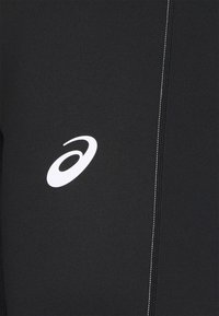 Svarta sportleggings i elastiskt material, med en vit logotyp och kontrasterande vit sömnad längs sömmarna.