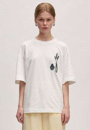 Witte katoenen t-shirt met een ontspannen pasvorm, uitgevoerd met zwarte geborduurde vazen en bladeren aan de linkerkant, korte mouwen en een ronde hals.