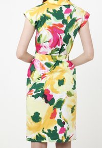 Kukallinen mekko, jossa on kirkkaat keltainen, vaaleanpunainen, vihreä ja valkoinen väri. Midi-pituus, lyhyet hihat ja vyötäröllä vyö, joka luo vartalonmyötäisen ilmeen.