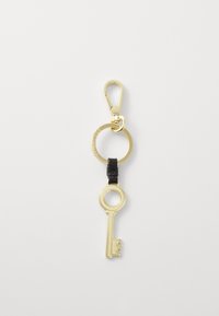 Portachiavi in metallo dorato con anello circolare, caratterizzato da un design a chiave scolpito. Un accentuazione in pelle nera collega la chiave all'anello.