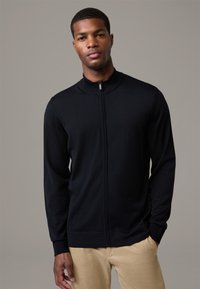 Marineblauer Reißverschluss-Pullover mit hohem Kragen und langen Ärmeln, aus weichem Strickstoff gefertigt. Eng anliegendes Design mit gerippten Bündchen und Saum.