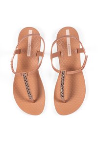 Beige Flip-Flops mit einer strukturierten Innensohle, dünnen Riemen und einem dekorativen Strassakzent am mittleren Riemen. Hergestellt aus flexiblem Material.