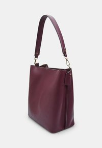 Burgundy bőr kézitáska egyetlen széles pánttal, téglalap alakú, sima felülettel és oldalsó cipzár részlettel.