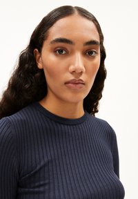 Navyblaue gerippte Langarm-Bluse mit rundem Ausschnitt, aus einem strukturierten Material und in figurbetonter Passform.