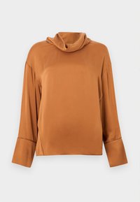 Μπλούζα μακρυμάνικη σε χρώμα σκουριάς με φαρδύ ζιβάγκο και φαρδιά μανίκια, σε απλό ανοιχτό γκρι φόντο.