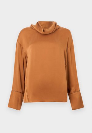 Roestkleurige blouse met lange mouwen, een losse col en brede manchetten, getoond op een effen lichtgrijze achtergrond.