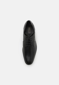 Scarpe eleganti da uomo in pelle nera con superfici lisce e testurizzate, design con lacci e un sottile dettaglio del logo sulla soletta.