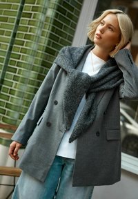 Gray wool blend blazer with a wide felt collar, paired with a white top and light blue jeans. Features double-breasted buttons and side pockets.