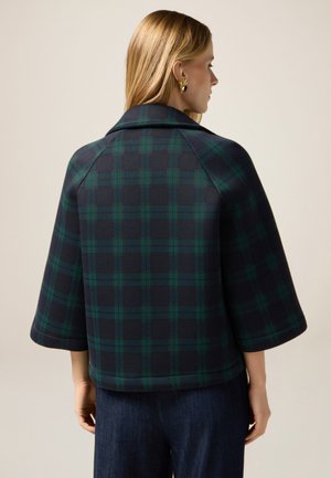 Kariertes Wolljackett in dunklem Marineblau und Grüntönen, mit einem breiten Kragen, kurzen Ärmeln und einer leicht strukturierten Form.