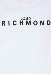 T-shirt in cotone bianco con un grande logo nero che recita "JOHN RICHMOND" in lettere maiuscole. Il tessuto ha una consistenza liscia.