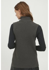 Szary żebrowany kamizelka z golfem o luźnym kroju, z wysokim kołnierzem i bezrękawnikowym fasonie, pokazana na czarnym topie z długim rękawem.