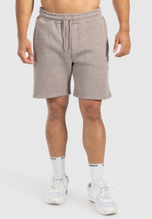 Szare szorty z bawełny z domieszką elastanu, z elastycznym paskiem w talii i sznurkiem, z bocznymi kieszeniami i luźnym krojem, w zestawieniu z białymi sneakersami.