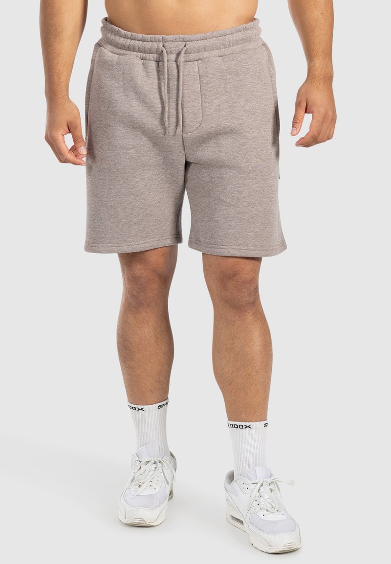Pantalones cortos de mezcla de algodón en color gris con cintura elástica y cordón, que presentan bolsillos laterales y un ajuste relajado, combinados con zapatillas blancas.
