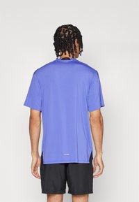 Blue athletic t-shirt with short sleeves, made from lightweight fabric, featuring a round neckline and side slits at the hem for flexibility.