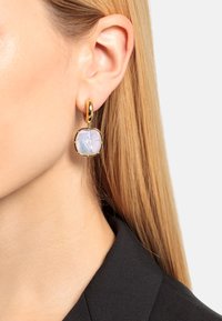 Gouden hoopoorbellen met een rechthoekige, iriserende steen met een subtiel patroon. Het ontwerp is modern met een strakke afwerking.