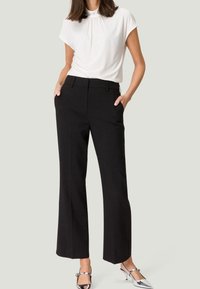 Zwarte taillepantalons met een recht model, hoge taille, zijzakken, gecombineerd met een short-sleeve witte top.