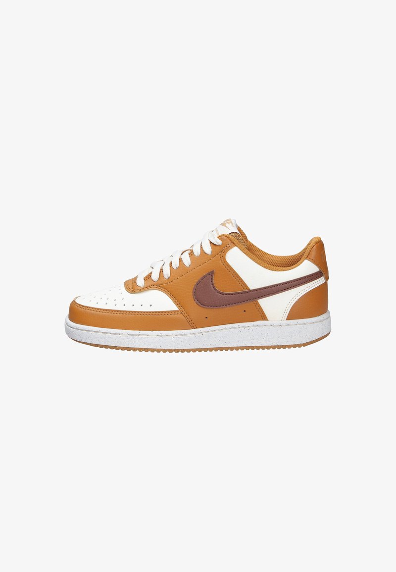 Scarpe Nike caratterizzate da una combinazione di pelle marrone e crema, punta perforata, lacci bianchi e una suola in gomma testurizzata con un design maculato.