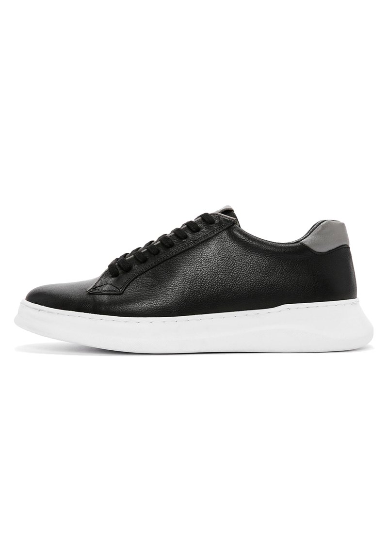 Baskets en cuir noir avec une finition texturée, dotées d'une semelle en caoutchouc blanche, d'un accent au talon gris et d'un design à lacets noirs.