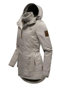 Giacca grigia chiara con cappuccio, dotata di zip frontale, due tasche laterali, polsini elasticizzati e un dettaglio in pelle marrone sulla manica.