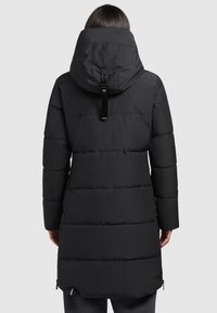 Black puffer coat with a hood, featuring quilted sections and a longer hem. Includes a hang tag and zippers at the sides for adjustment.