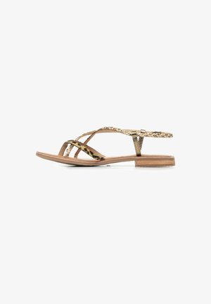 Sandali flat a motivo oro e nero con cinturini incrociati, caratterizzati da un design intrecciato e una suola sottile e piatta di tonalità legno naturale.