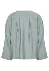 Lyseblå, tekstureret bluse med en afslappet pasform, drop-skuldrer og rund halsudskæring. Ryggen har bløde plisseringer for ekstra detalje.