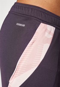 Sudadera activa Aeroready en gris oscuro con panel lateral de malla rosa. Presenta una cinturilla elástica y sutiles acentos de patrón.