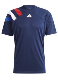Námořnická modrá sportovní košile s krátkým rukávem, s červenými, bílými a modrými diagonálními pruhy na levém rameni a bílým logem Adidas na hrudi.