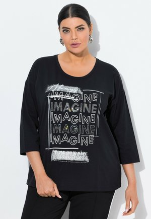 Musta pitkähiha t-paita, jossa on pyöreä kaula-aukko ja "IMAGINE" -grafiikkasuunnittelu, jossa on metallisia yksityiskohtia ja teksturoitu painatus.