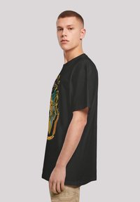 Black cotton t-shirt featuring a colorful graphic design on the front, depicting a shield and decorative elements. Loose fit and short sleeves.