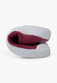 Chaussure en toile bordeaux avec une semelle en caoutchouc blanche, présentant un bout rond et un col légèrement rembourré, affichée en position pliée.