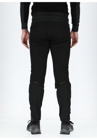 Zwarte sportlegging met een slank design, voorzien van een brede tailleband en zijzakken met rits. Inclusief subtiele bergafbeeldingen nabij de zoom.