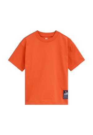 Pomarańczowy T-shirt z krótkim rękawem i okrągłym dekoltem, z małą prostokątną naszywką z motywem góry i słońca blisko dolnego brzegu po prawej stronie.