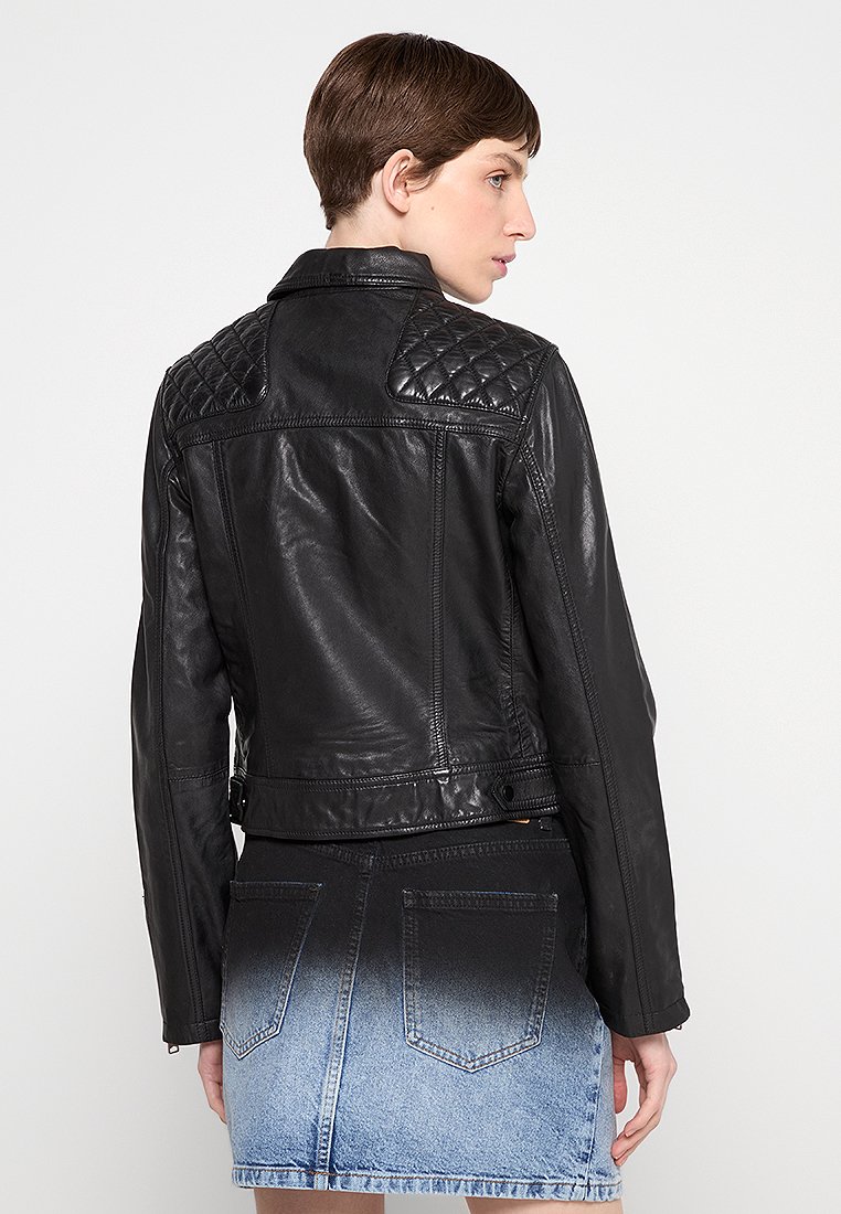 Giacca di pelle nera con accenti trapuntati sulle spalle, design aderente e vita regolabile. Abbinata a una mini gonna di denim sbiadito.