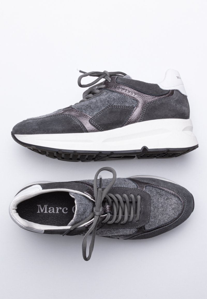 Paire de baskets en daim gris foncé et noir avec semelles blanches, vues de dessus et de côté, avec lacets et cols rembourrés.