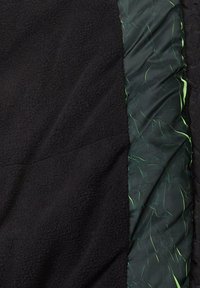 Tessuto in pile nero abbinato a un materiale verde scuro, leggermente arricciato, con accenti verde chiaro. Design testurizzato e stratificato.