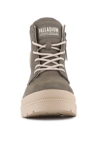 Bottine en cuir gris avec semelle en caoutchouc beige, bout rond et lacets plats. Présente un patch logo sur le côté et un panneau latéral texturé.