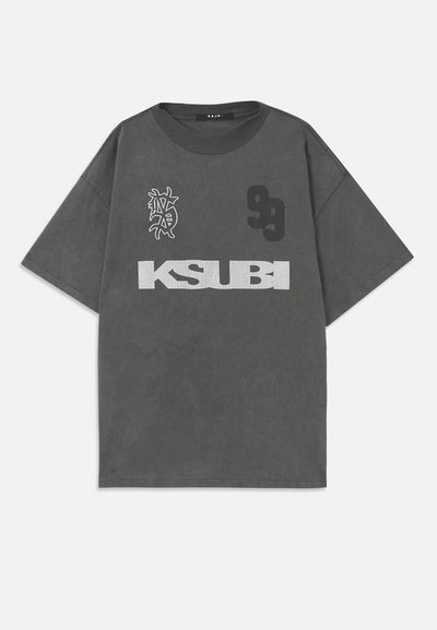 Gray oversized t-shirt with a round neckline. Features white "KSUBI" text, number "99," and a graphic design. Made of soft fabric.