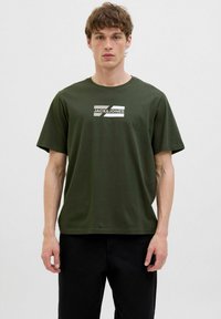 Grøn bomulds T-shirt med korte ærmer, præget af et hvidt grafisk design med mærkenavnet "JACK & JONES" på forsiden.