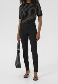 Svarta skräddarsydda byxor med smal passform, som har framfickor och knappstängning. Kombinerat med en kortärmad t-shirt randig i svart och vitt.