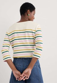 Striped long-sleeve top in cream, featuring horizontal stripes in green, pink, yellow, and navy; round neckline and relaxed fit.