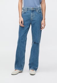 Jeans din denim albastru deschis cu croială relaxată, având o despicătură frontală, design cu cinci buzunare și talie medie. Textură moale.