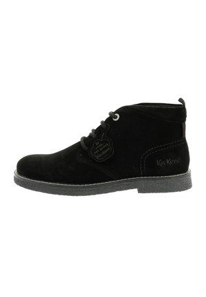 Botas de tobillo de ante negro con ojales plateados, atadas con cordones, que presentan una suela texturizada y una etiqueta con el logo de Kickers en el lateral.