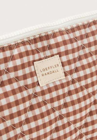 Καπιτονέ υφασμα καφετί και λευκό καρό με διαγώνιες ραφές και μπεζ υφασμάτινη ετικέτα με την επιγραφή "Loeffler Randall" κοντά σε λευκό φερμουάρ.