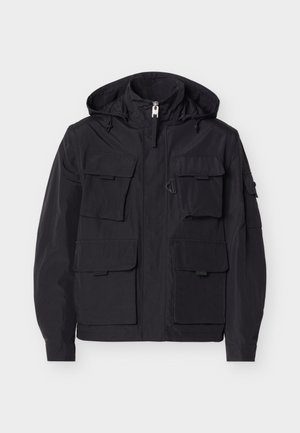 Czarna kurtka z kapturem, zapinana na zamek z przodu, z sześcioma kieszeniami na patki, wyposażona w regulowane sznurki w kapturze oraz długie rękawy z zapięciami na mankiety.