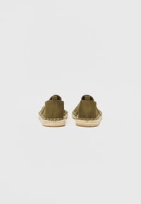 Olive green espadrilles with a canvas upper, featuring a jute rope sole, low back, and slip-on design. Smooth texture with minimal detailing.